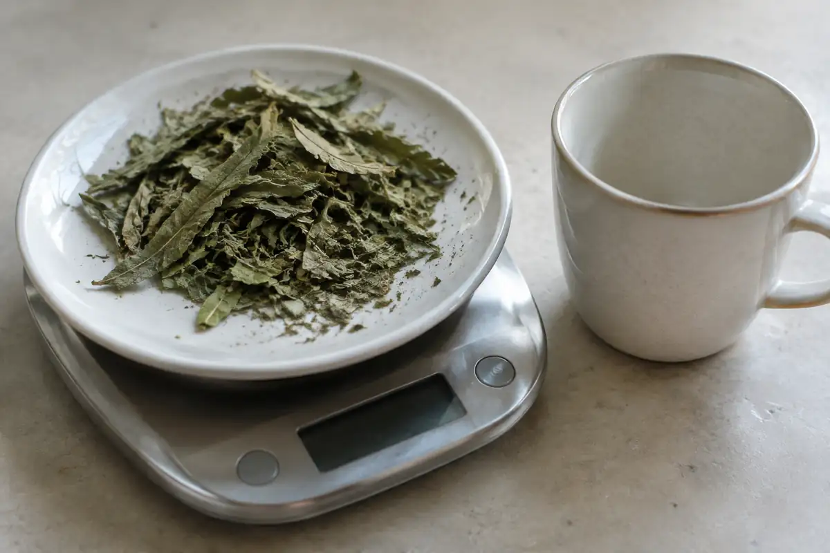 Feuilles de verveine odorante séchées posées sur le plateau d'une petite balance de cuisine
