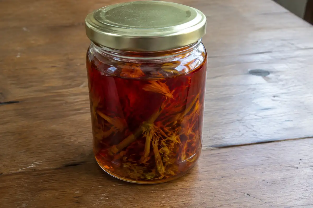 Bocal d'huile rouge de millepertuis posé sur une table en bois